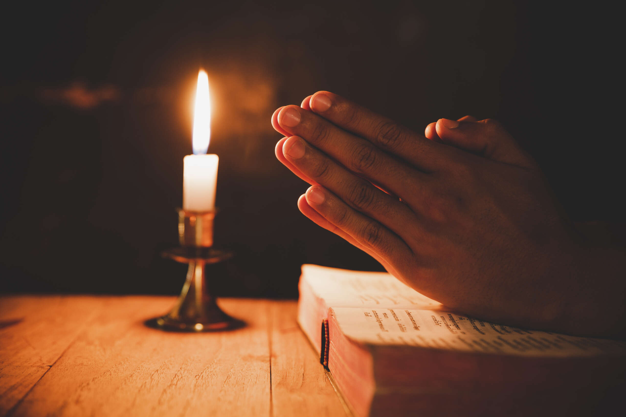 man praying on the Bible in the light candles selective focus