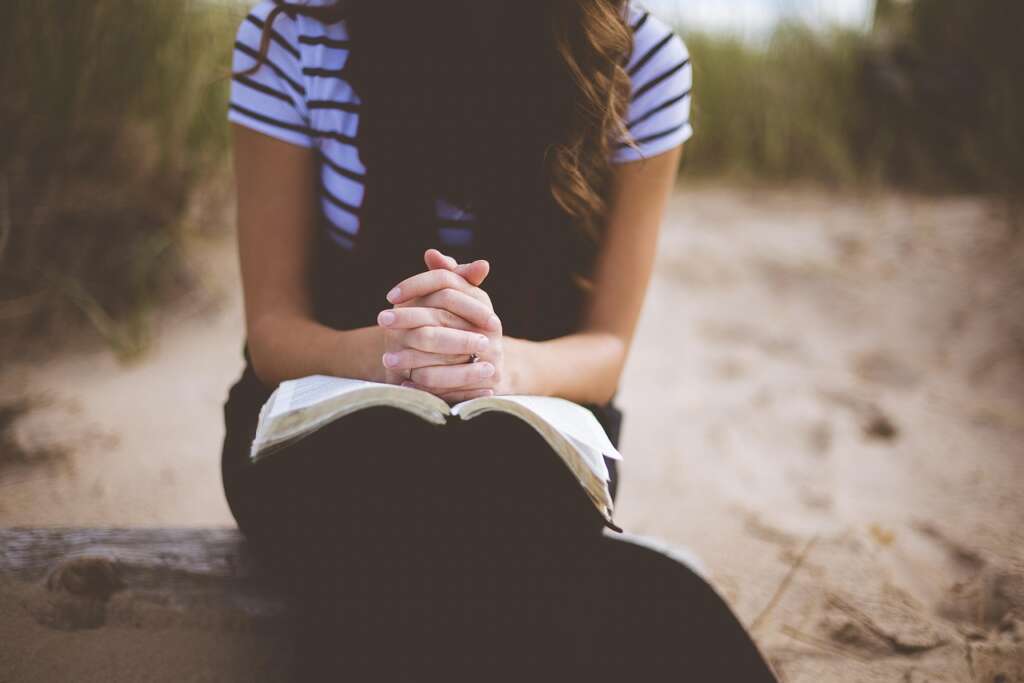 Person reflecting quietly while seeking spiritual reconnection through prayer, faith, and digital devotion