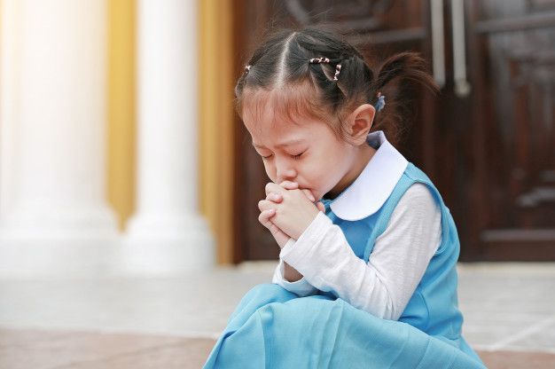Young child sitting in quiet, peacefully praying at home
